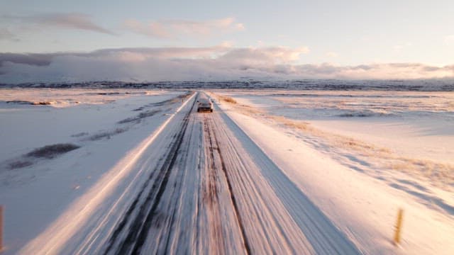 Car driving on a snowy road at sunrise