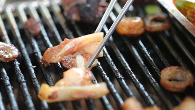 Grilled pork belly cartilage being picked up with chopsticks