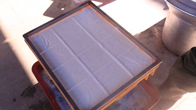 Person preparing homemade tofu outdoors