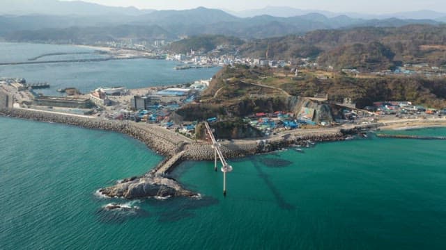 Coastal Town with Pier and Mountains in the Distance