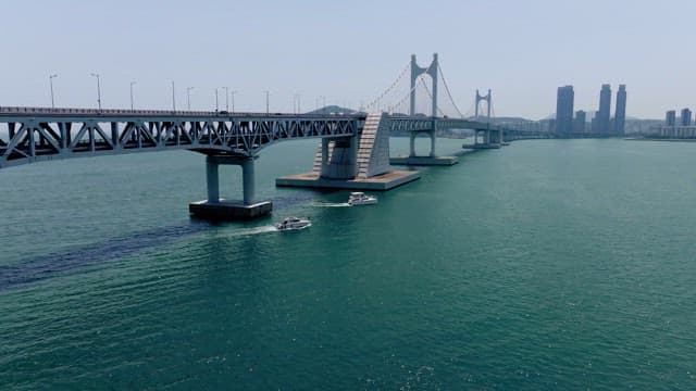 Yachts passing under the Gwangan Bridge on a clear day with lots of cars