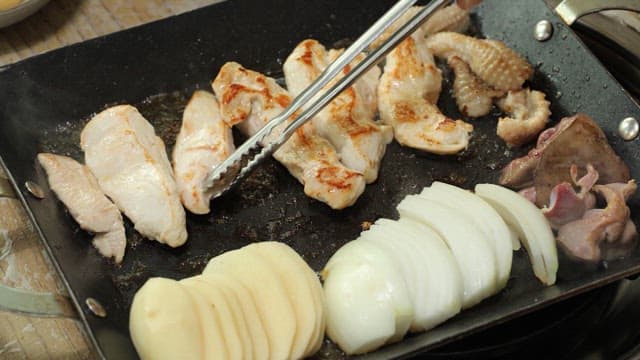 Chicken grilled on a hot iron plate with potatoes and onions
