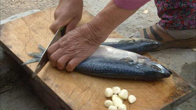 Elderly Person Preparing Fish Outdoors