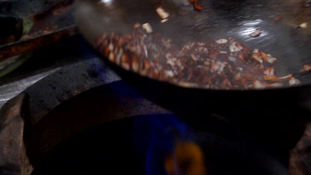 Making Jjajang sauce by stir-frying black bean paste, vegetables, and meat in a wok