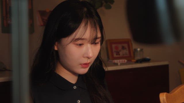 Woman sitting indoors with a thoughtful expression