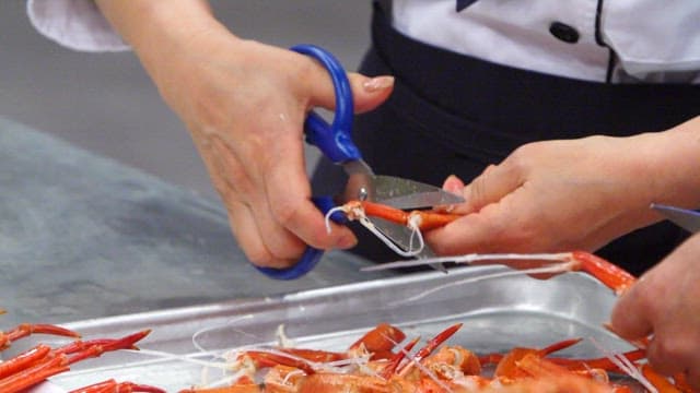 Red crab legs being cut with scissors