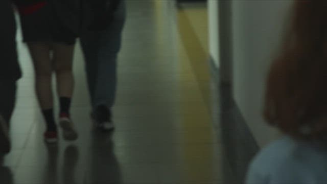 Student picking up scattered papers in a dimly lit hallway