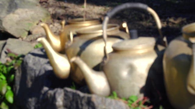 Outdoor setting with antique brass kettles on stone