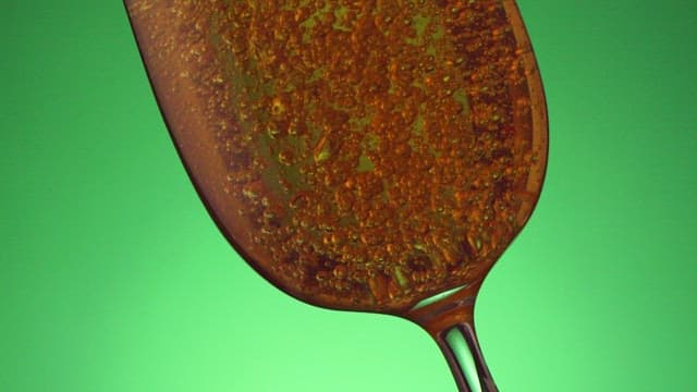 Bubbling liquid in a wine glass against a green background