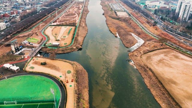 Urban River Flanked by Roads and Fields