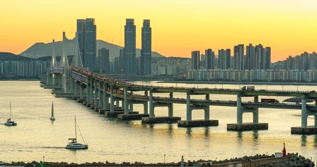 Evening view of a bustling port city Busan with tall skyscrapers and Gwangan Bridge