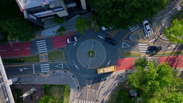 Busy urban roundabout surrounded by buildings and lush greenery.