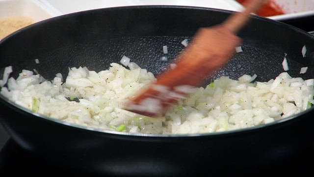 Onions being sautéed in a pan