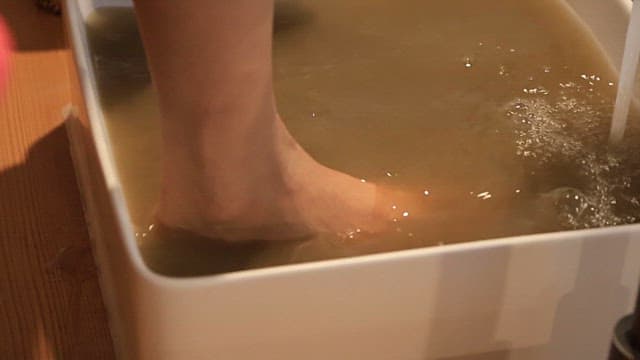 Person soaking feet in warm foot bath for relaxation