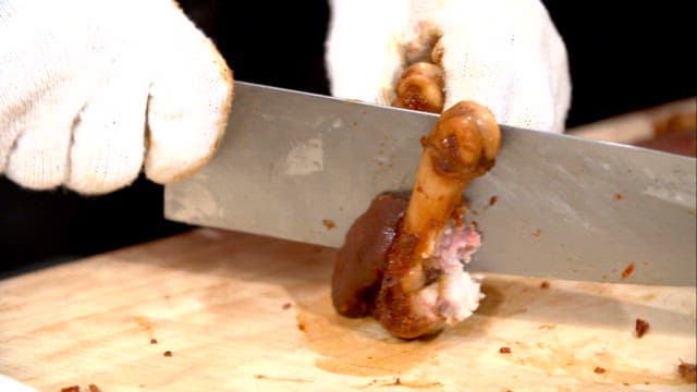 Cutting braised pigs' feet on a board