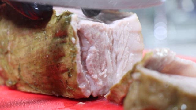 Someone slicing boiled meat on a cutting board