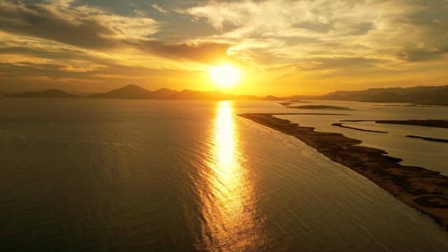 Sunset over a calm sea with distant mountains