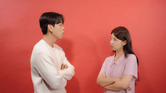 Man and a woman glowering at each other with their arms linked