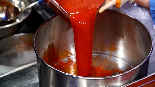 Pouring red sauce into a large pot