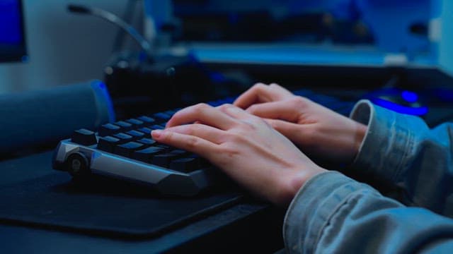 Hands typing rapidly on a backlit keyboard