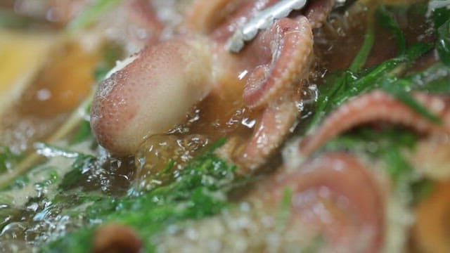 Cutting the webfoot octopus in a broth with vegetables