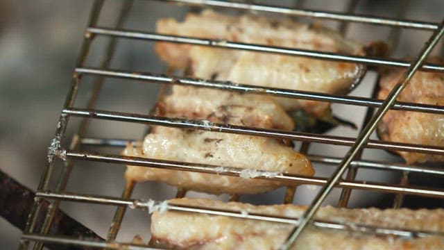 Eels grilling on a barbecue over coals