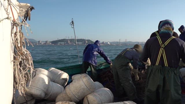 Fishermen preparing nets on a fishing boat at sea