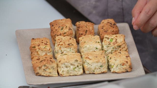 Freshly baked green onion scones being arranged on a tray
