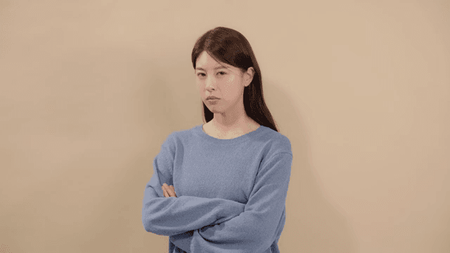 Woman with a disgruntled expression, looking ahead with her arms crossed