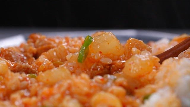 Spoonful of rice bowl with stir-fried radish and pork mixed with a spoon