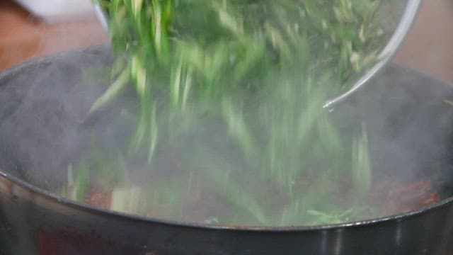 Freshly chopped green chili peppers in a steaming wok