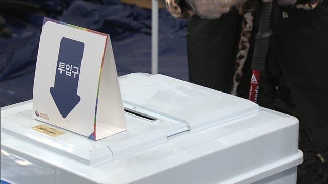 Person casting a vote in an indoor voting booth wearing disposable gloves