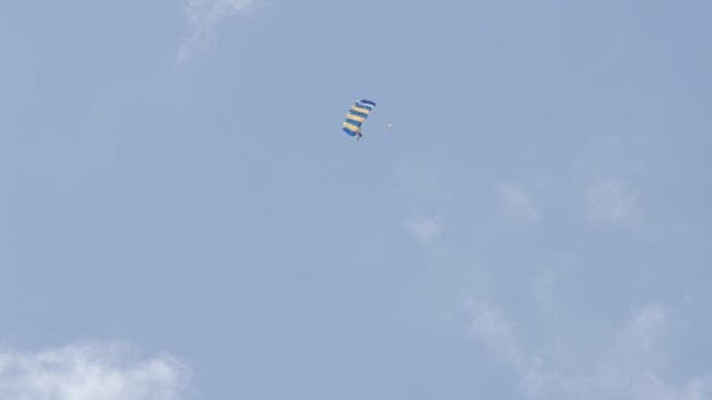 Skydivers descending with a parachute