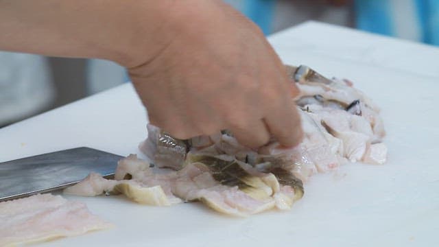 Slicing fresh conger eel on a cutting board