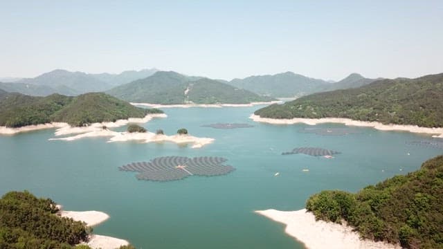 Floating solar panels on a lake surrounded by green hills