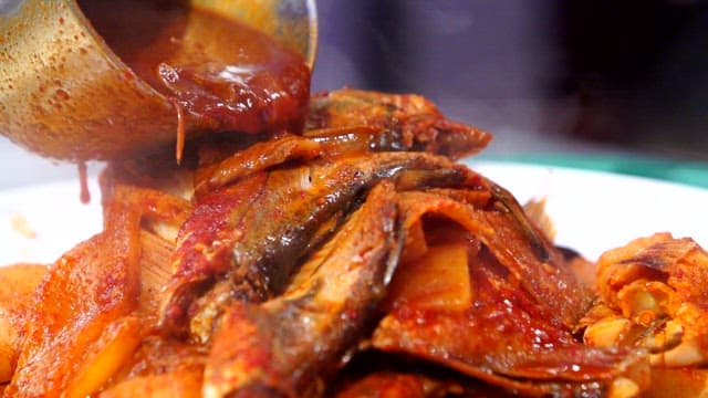 Spicy assorted braised fish with sauce being poured