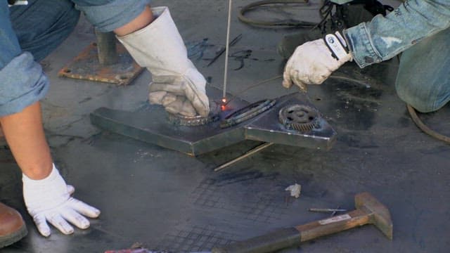 Welders working on a metal gear structure outdoors