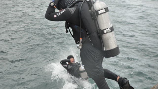 Divers jumping into the sea from a boat