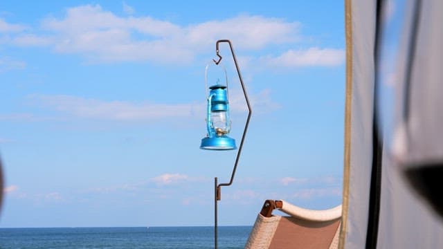 Blue camping lantern hanging against a clear sky by the sea
