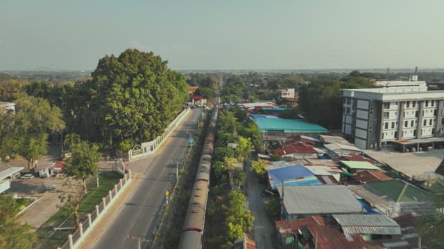 Train Moving through a Residential Area with Surrounding Greenery and Buildings