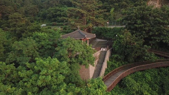 Traditional Korean pavilion and bell amidst lush greenery