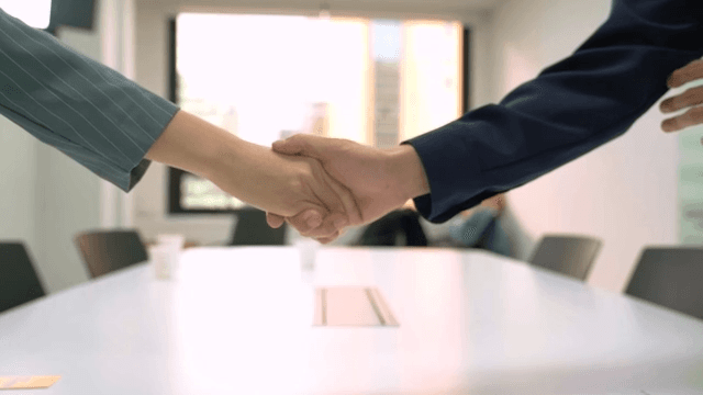 Two people standing and shaking hands in an office