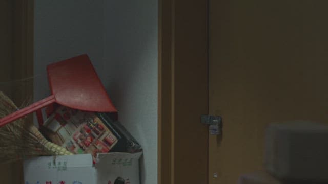 Woman unlocking a door in a dimly lit room with cleaning supplies