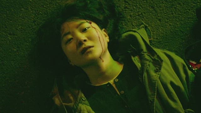 Woman lying on the street at night with her head bleeding