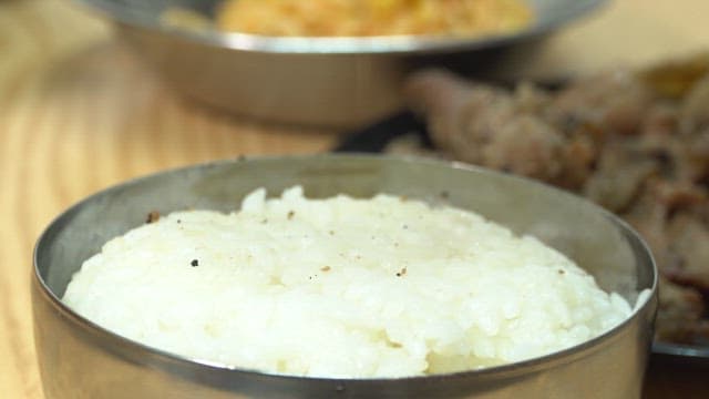 Hands making a lettuce wrap with grilled meat and vegetables