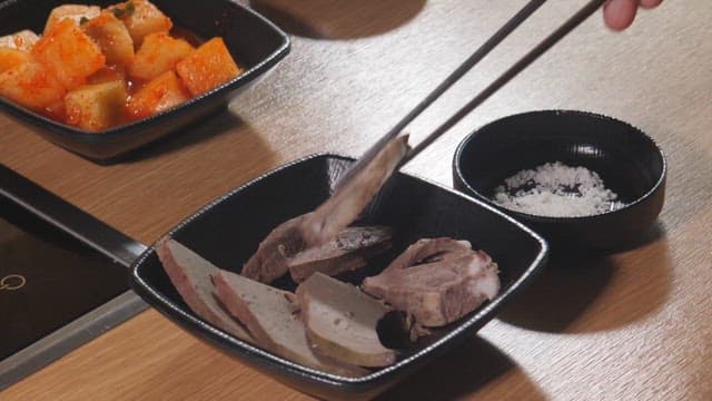Slices of liver being dipped into salt