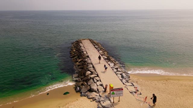 People walking on a stone pier by the sea