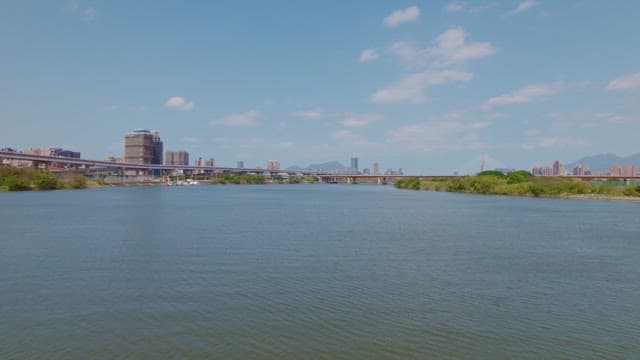 Calm river with a city skyline and bridge