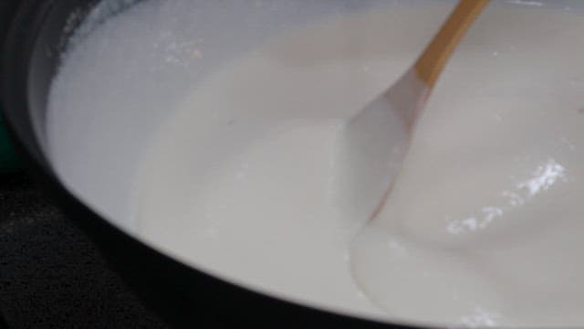 Mixing of thick white batter in a large bowl using wooden spatulas