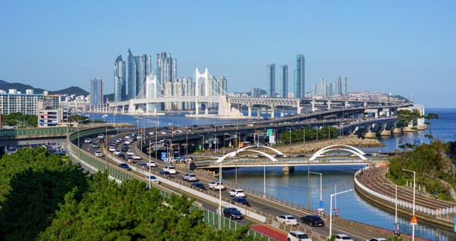 From day to night view of a bustling port city with tall skyscrapers and bridge